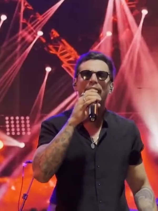 Matheus Rhauny cantando em palco tomado por refletores vermelhos