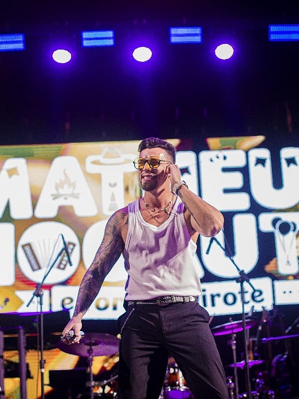 Matheus Rhauny no palco principal diante do telão com o nome da banda